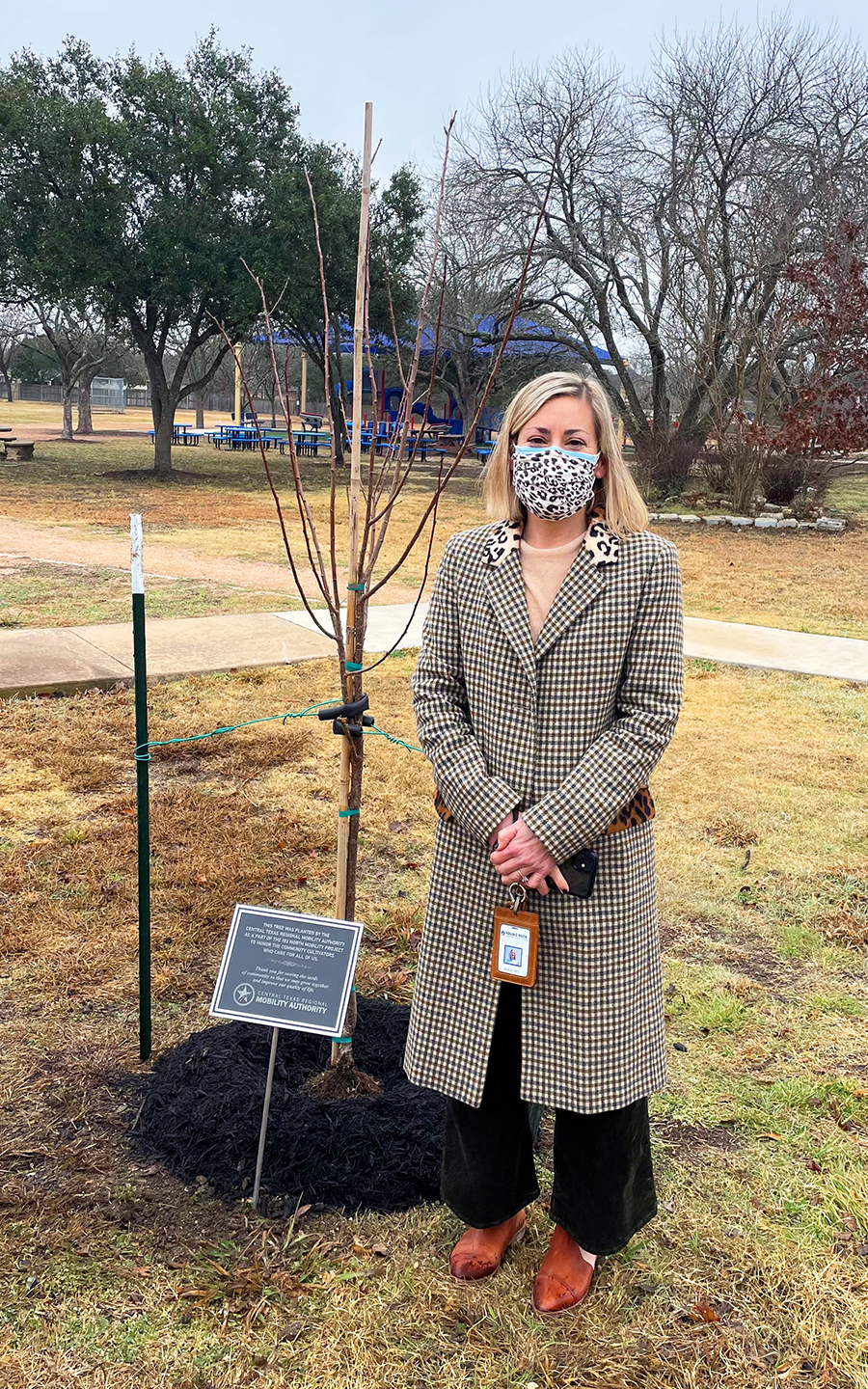 Principal Alicia Hill stands next to a young Mexican plum tree on the Spicewood Elementary school grounds.